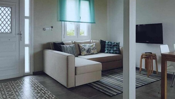 A living room with a sofa, a television, and a window with a curtain. - Restored fisherhouse for 6 persons (Lira (Santa Maria))