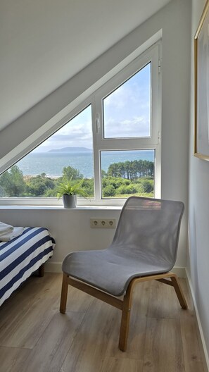 Une pièce comprenant un lit, une chaise et une fenêtre donnant sur un paysage.