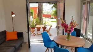 An open-plan living area with a sofa, a table, chairs, and a potted plant. - Bungalow n°6 on the Lighthouse Road (Lariño)