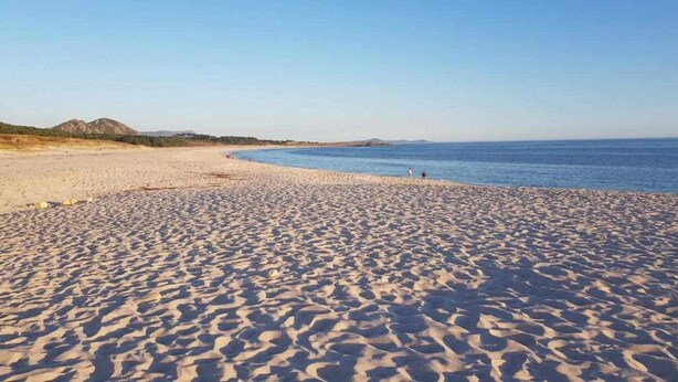 A sandy beach with a clear sky and distant mountains. - Bungalow n°6 on the Lighthouse Road (Lariño)
