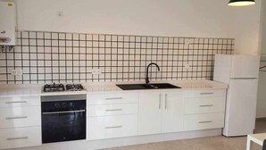 A kitchen with white cabinets, a black sink, and a stove. - Bungalow n°6 on the Lighthouse Road (Lariño)