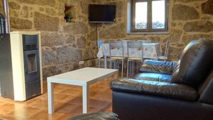 Une pièce aux murs de pierre, dotée d’une cheminée, d’un téléviseur fixé au mur, d’une table à manger avec des chaises et d’un canapé en cuir.