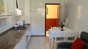 Una cocina compacta con armarios blancos, una estufa a gas y un comedor con mesa y sillas.