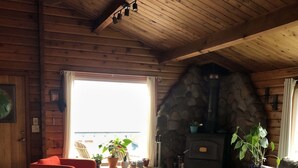 A cozy cabin interior with a stone fireplace, wooden walls, a red chair, and a gray sofa. - Good Vibes Cabin - Car rental available! (Craig)