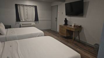 Une chambre d’hôtel avec deux lits simples, un bureau en bois, un téléviseur à écran plat et une fenêtre avec des rideaux.