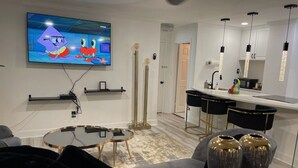 Una sala moderna con una televisión de pantalla plana, una mesa redonda de centro y un sofá.