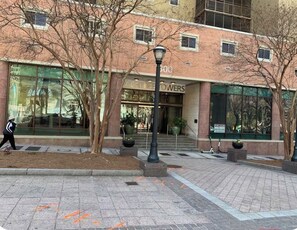 A building with a storefront labeled 'ACHIEVEMENT FLOWERS' and a 'FOR LEASE' sign.