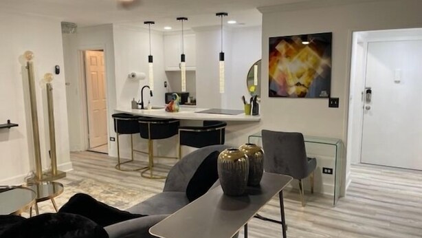 Un salón moderno con comedor, una cocina al fondo y un cuadro abstracto grande en la pared.