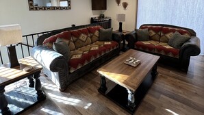 A living room with two sofas, a coffee table, and a ceiling fan.