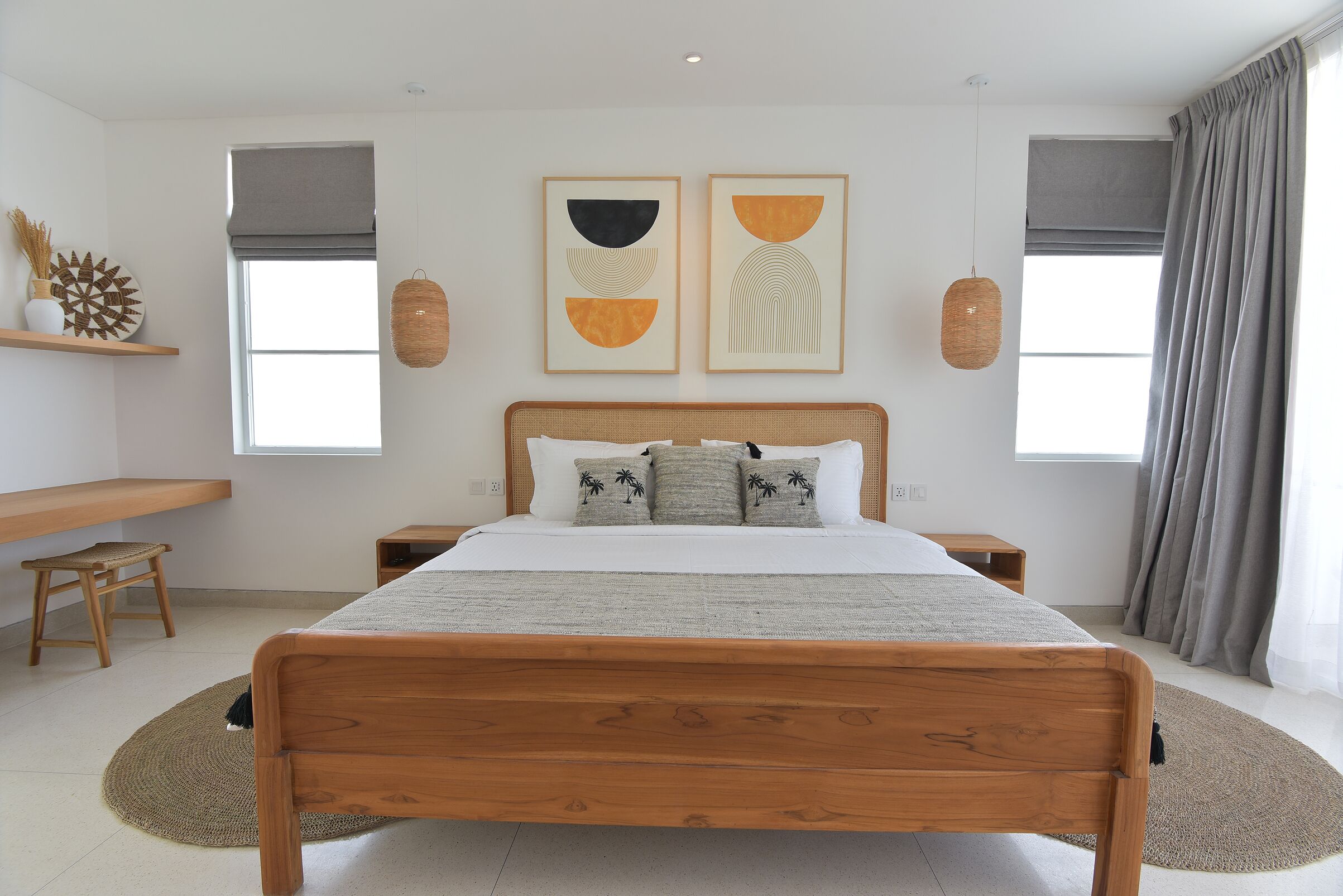 A bedroom with a wooden bed, a bedside table, a chair, and two windows with curtains.