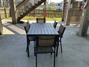 Une terrasse en bois avec une table de pique-nique et des chaises, entourée d’une clôture en bois et d’un escalier.