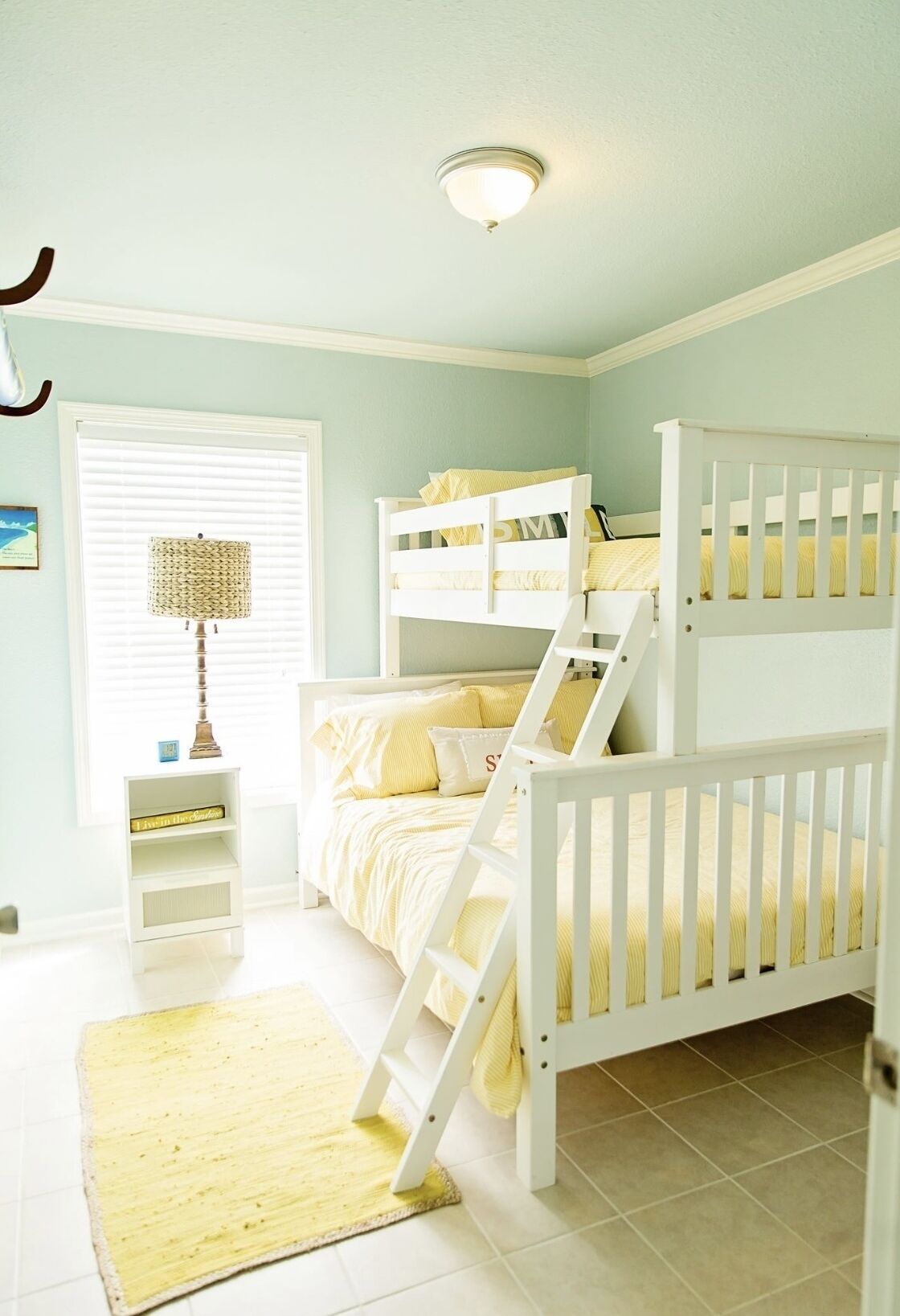 Ein Kinderzimmer mit Etagenbetten, einem kleinen Tisch und einer Lampe.