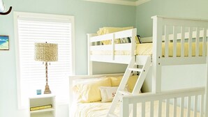 Ein Kinderzimmer mit Etagenbetten, einem kleinen Tisch und einer Lampe.