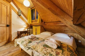 Una habitación de madera con una cama, una mesa y un ventanal con cortinas.
