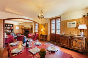 Un comedor con una mesa de madera dispuesta para una comida, una chimenea y una estantería.