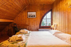 Una habitación de madera con una cama, una ventana, un radiador y un cuadro en la pared.