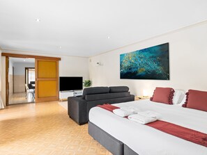 A modern hotel room with a large bed, a sofa, a flat-screen TV, and a painting on the wall. - Swainson on Margaret (North Brighton)