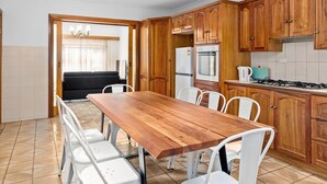 A modern kitchen with wooden cabinets, a dining table, and chairs. - Swainson on Margaret (North Brighton)