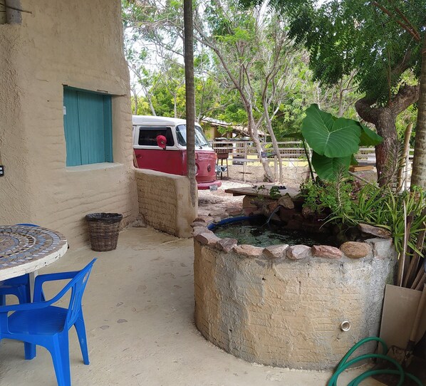 A courtyard with a small table and chairs, a concrete water feature, and a parked vehicle. - casa de areia (Aracati)