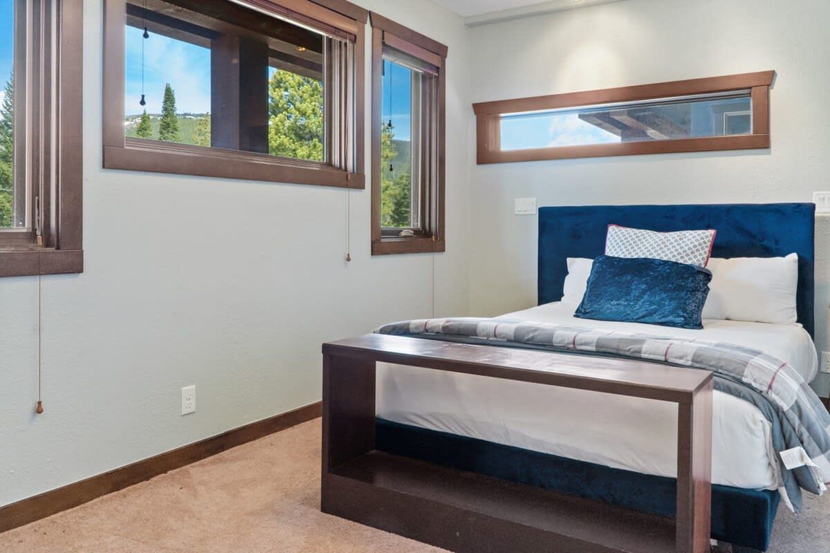 A bedroom with a bed, a nightstand, a window, and a mirror.