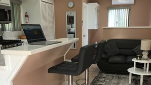 Un espacio habitable compacto con kitchenette, una zona de comedor con taburete de bar y un sofá.