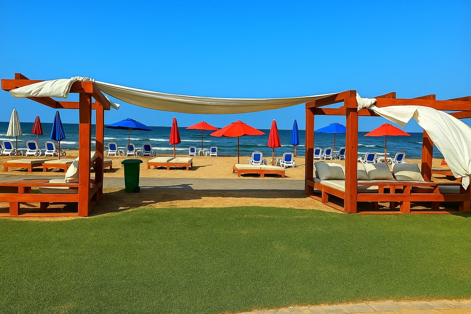 Eine Strandlounge mit Holzliegen, roten und blauen Sonnenschirmen und freiem Blick auf das Meer.