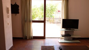 A living room with a television on a stand, a remote control, and a patterned rug on the floor. - Marina Gardens, Relaxing Duplex in Central Location (Quarteira)