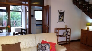 A living room with a beige sofa, a wooden side table, and a staircase. - Marina Gardens, Relaxing Duplex in Central Location (Quarteira)