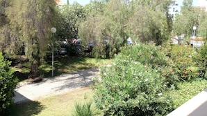 A garden area with trees and shrubs, a gravel path, and parked cars. - Marina Gardens, Relaxing Duplex in Central Location (Quarteira)