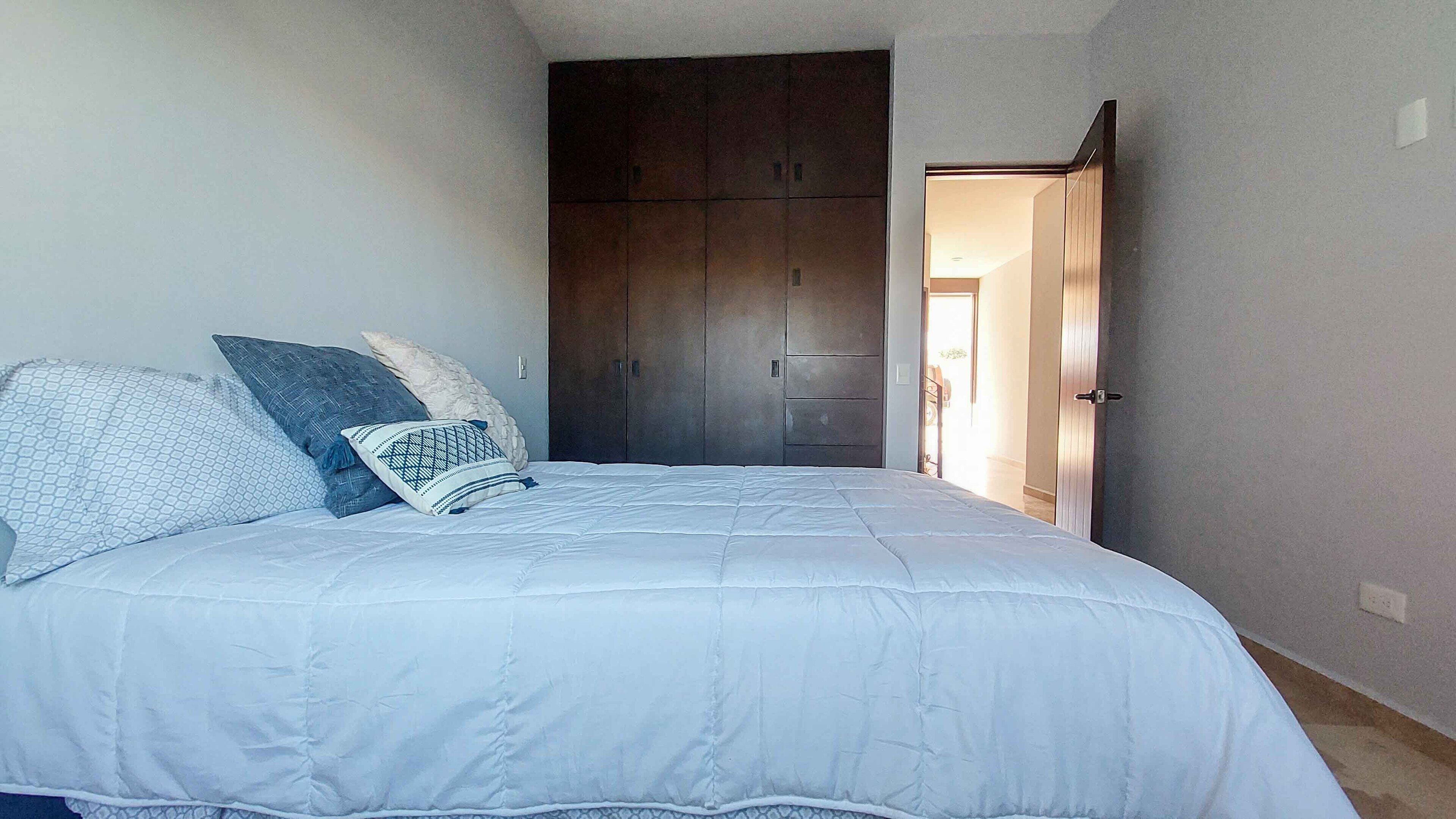 Een slaapkamer met een groot bed, een kledingkast en een deur naar een andere kamer.