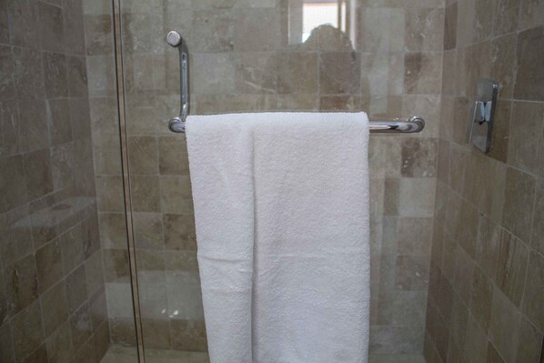 A glass shower enclosure with a white towel hanging on a metal towel bar.