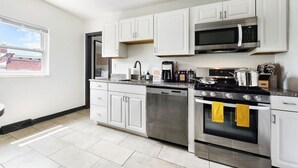 Una cocina moderna con armarios blancos, electrodomésticos de acero inoxidable y una ventana con vistas al exterior.