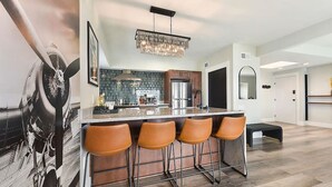 Una cocina moderna con una isla central, taburetes de bar y una lámpara de araña.