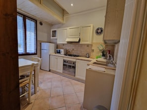 Compact kitchen with essentials: refrigerator, microwave, stove, sink, and window.