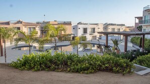 A modern residential area with multiple buildings, a central courtyard with a pool, and surrounding greenery. - Private Villa in Gated Community (Cabo San Lucas)