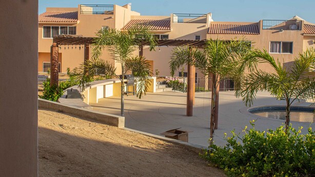 A residential area with multiple buildings, a swimming pool, and palm trees. - Private Villa in Gated Community (Cabo San Lucas)