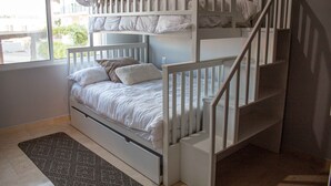 A bunk bed with a white railing, a window with a view of greenery, and a patterned rug on the floor. - Private Villa in Gated Community (Cabo San Lucas)