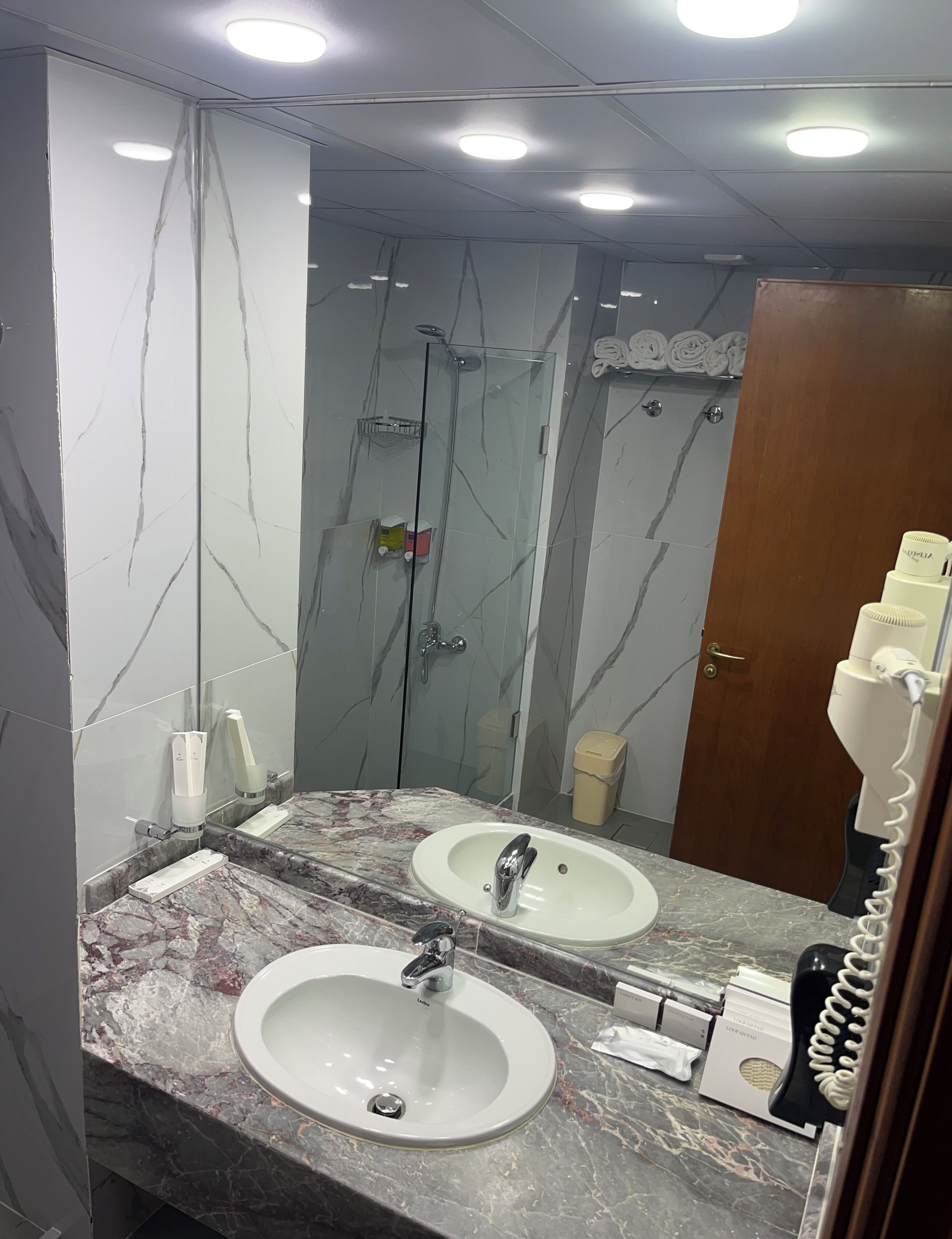 A bathroom with two sinks, a glass shower enclosure, and a mirror.