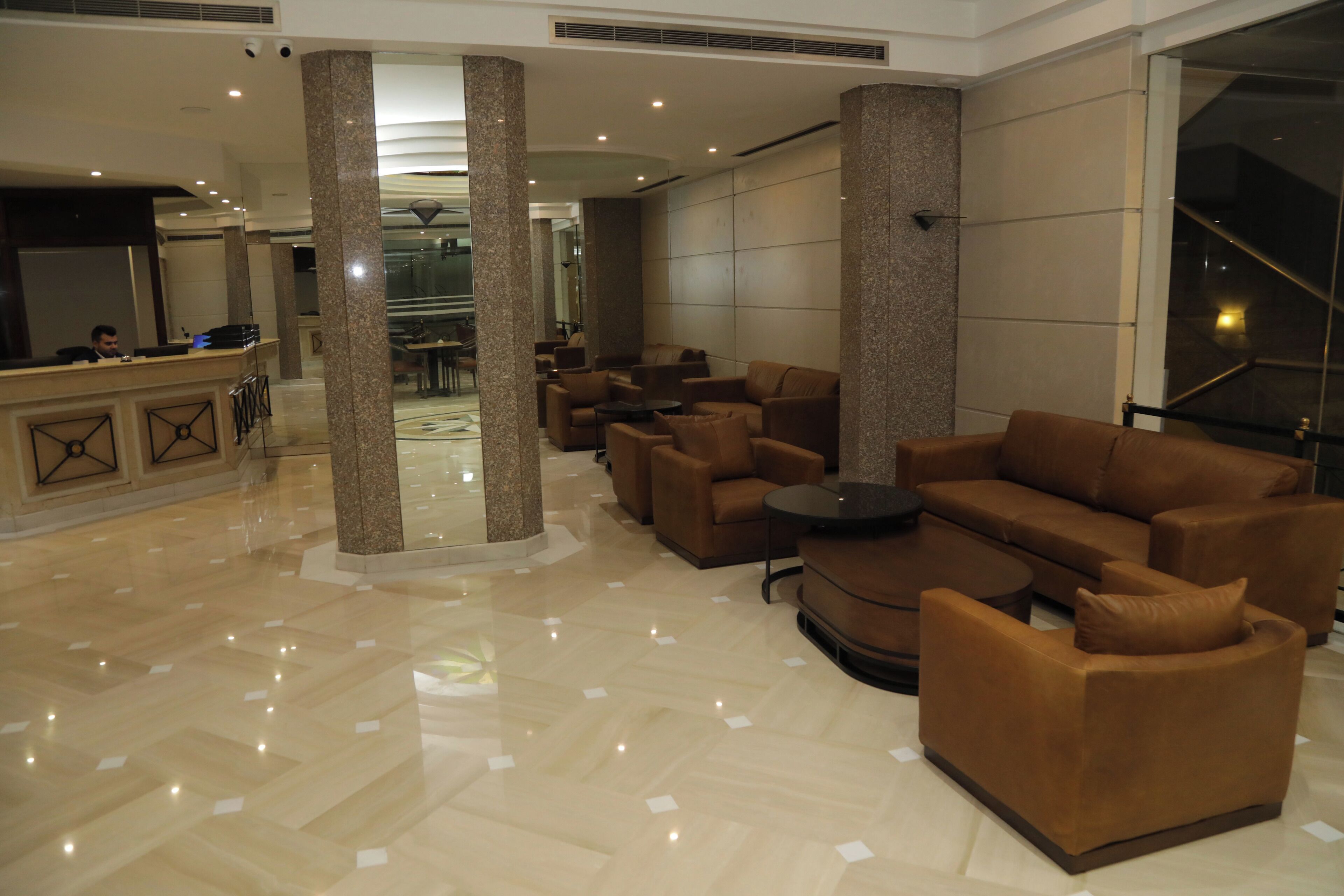 Un vestíbulo amplio con una mesa de recepción, varios sofás y una escalera.