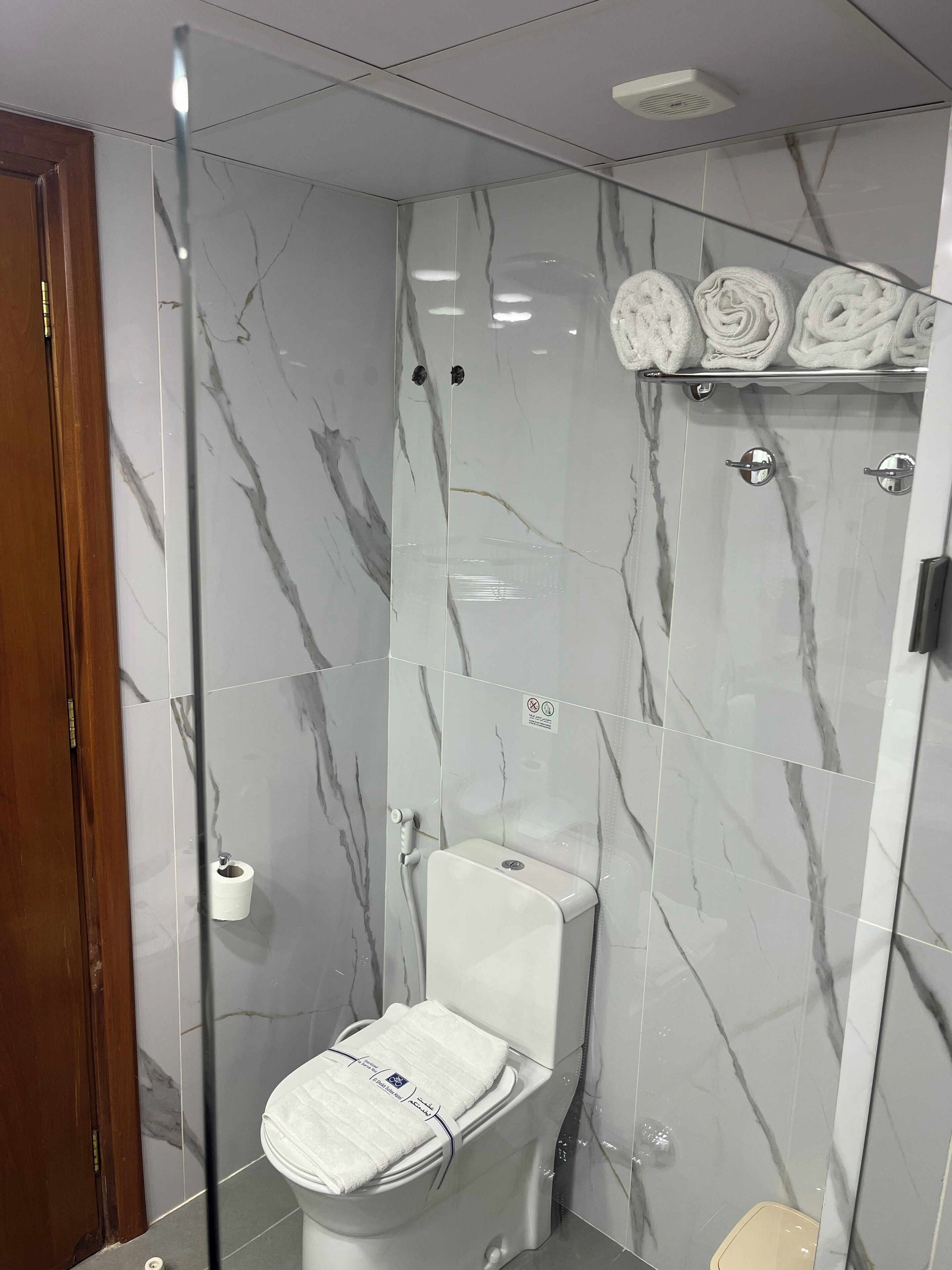 Un baño con inodoro, ducha y zona de ducha con mampara de vidrio.