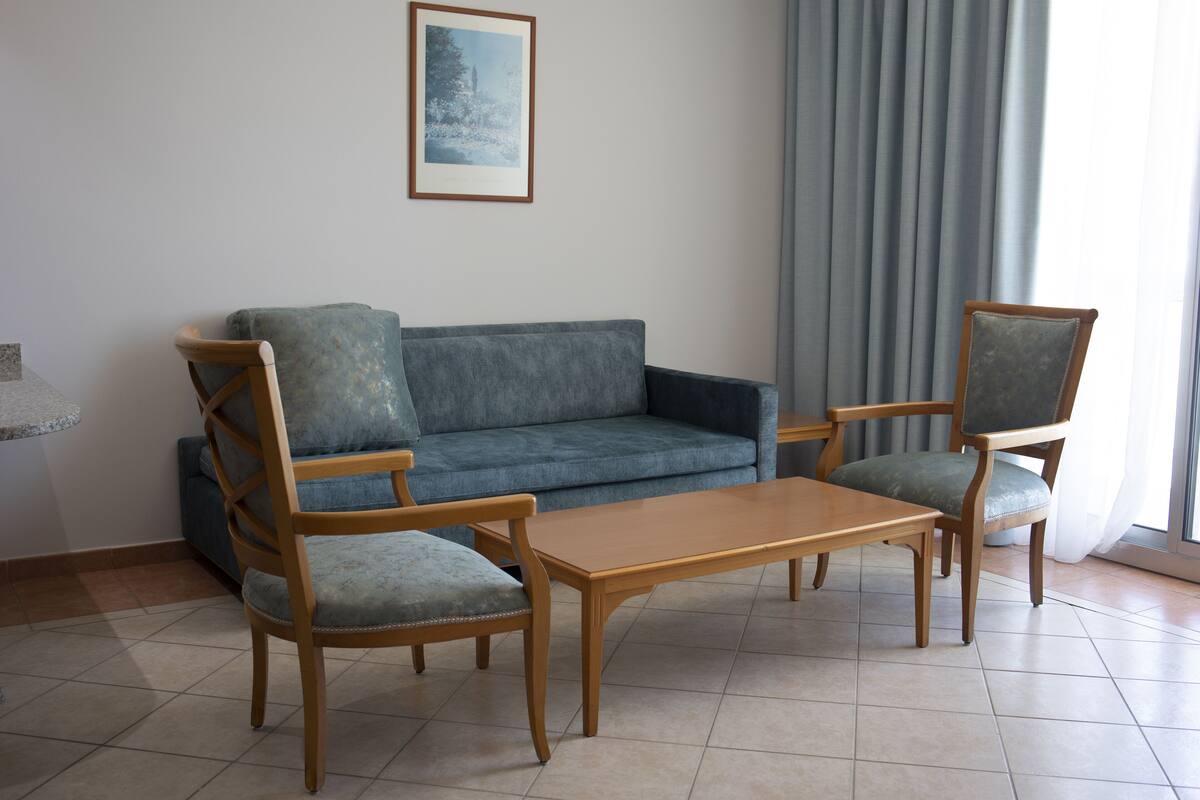 A living room with a blue sofa, two wooden chairs, and a wooden coffee table.