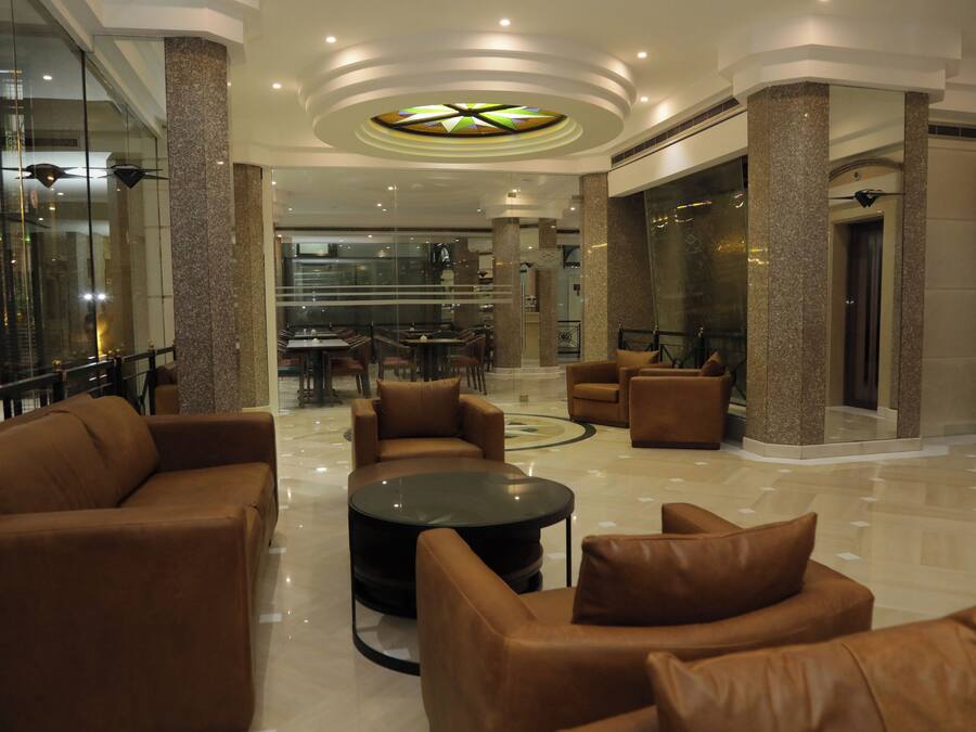 Un lobby espacioso con sofás de cuero, una mesa de centro y un ascensor de vidrio.