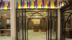 A hotel lobby with a glass entrance, two brown armchairs, a circular floor design, and a decorative ceiling. - El Sheikh Suites Hotel (Beirut)