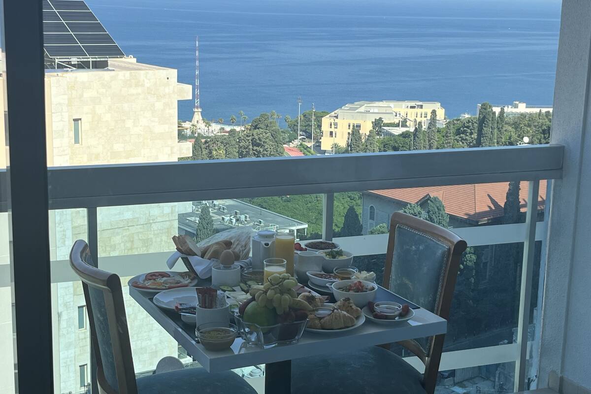 A balcony with a table set for breakfast overlooking the sea.