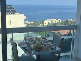 Un balcón con mesa dispuesta para el desayuno y vista al mar.