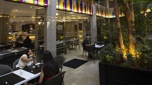An indoor dining area with tables and chairs, a glass ceiling, and a central column. - El Sheikh Suites Hotel (Beirut)