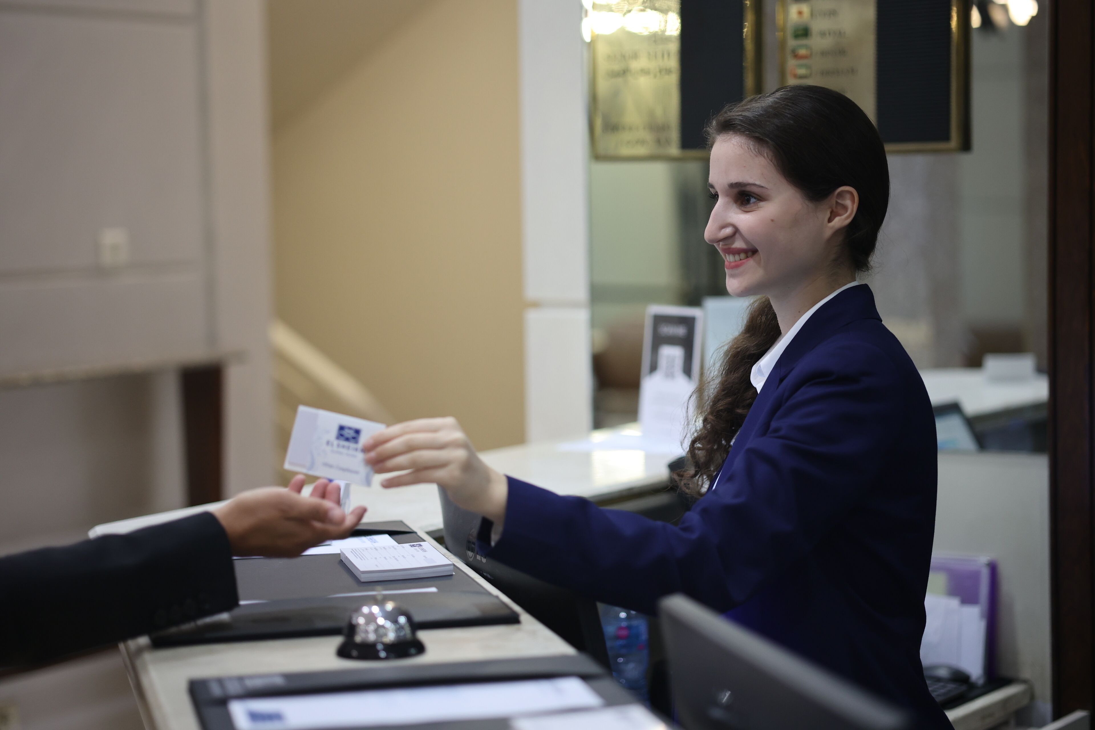 A reception desk with a person handing over a card to another individual.