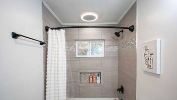 A modern bathroom with a freestanding bathtub, a toilet, and a sink with a granite countertop.