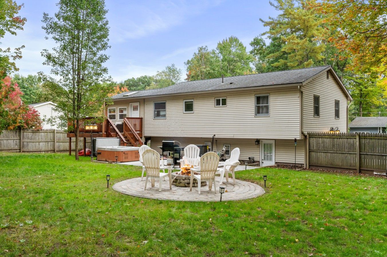 A two-story house with a backyard patio featuring outdoor furniture.