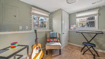 A room with a guitar, a keyboard, and a chair with a colorful cushion.